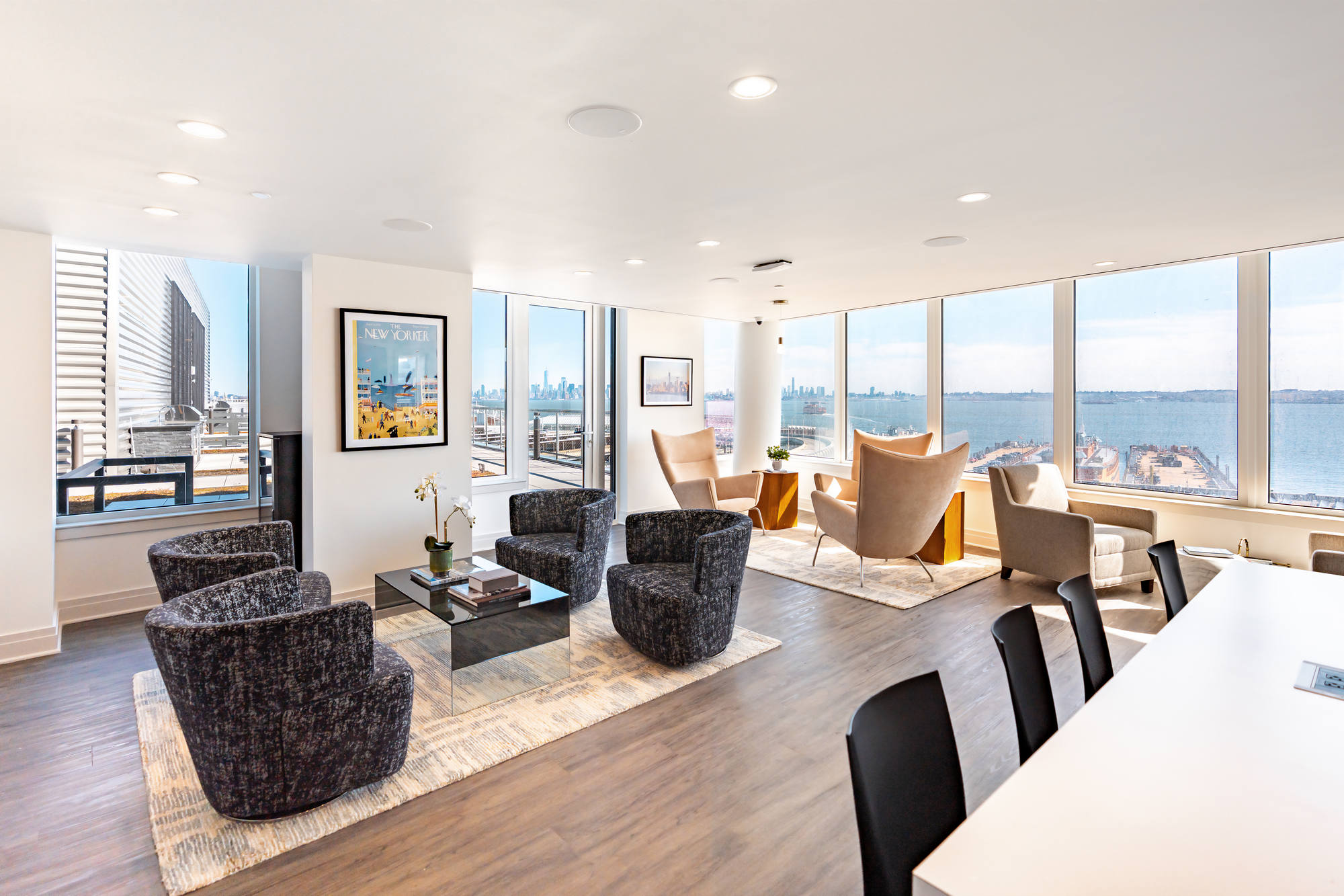 Bright modern lounge with large windows and wood floors, water views, ample seating including cozier areas plus conference table